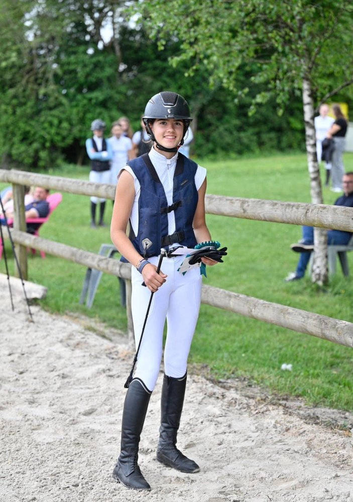 Jeune cavalière souriante en tenue de concours aux Écuries de Saint-Amand