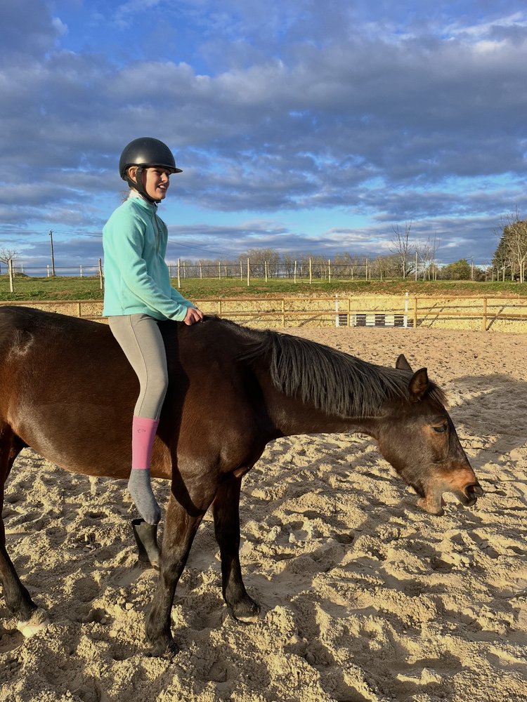 Jeune cavalière souriante à cheval, coucher de soleil aux Écuries de Saint-Amand