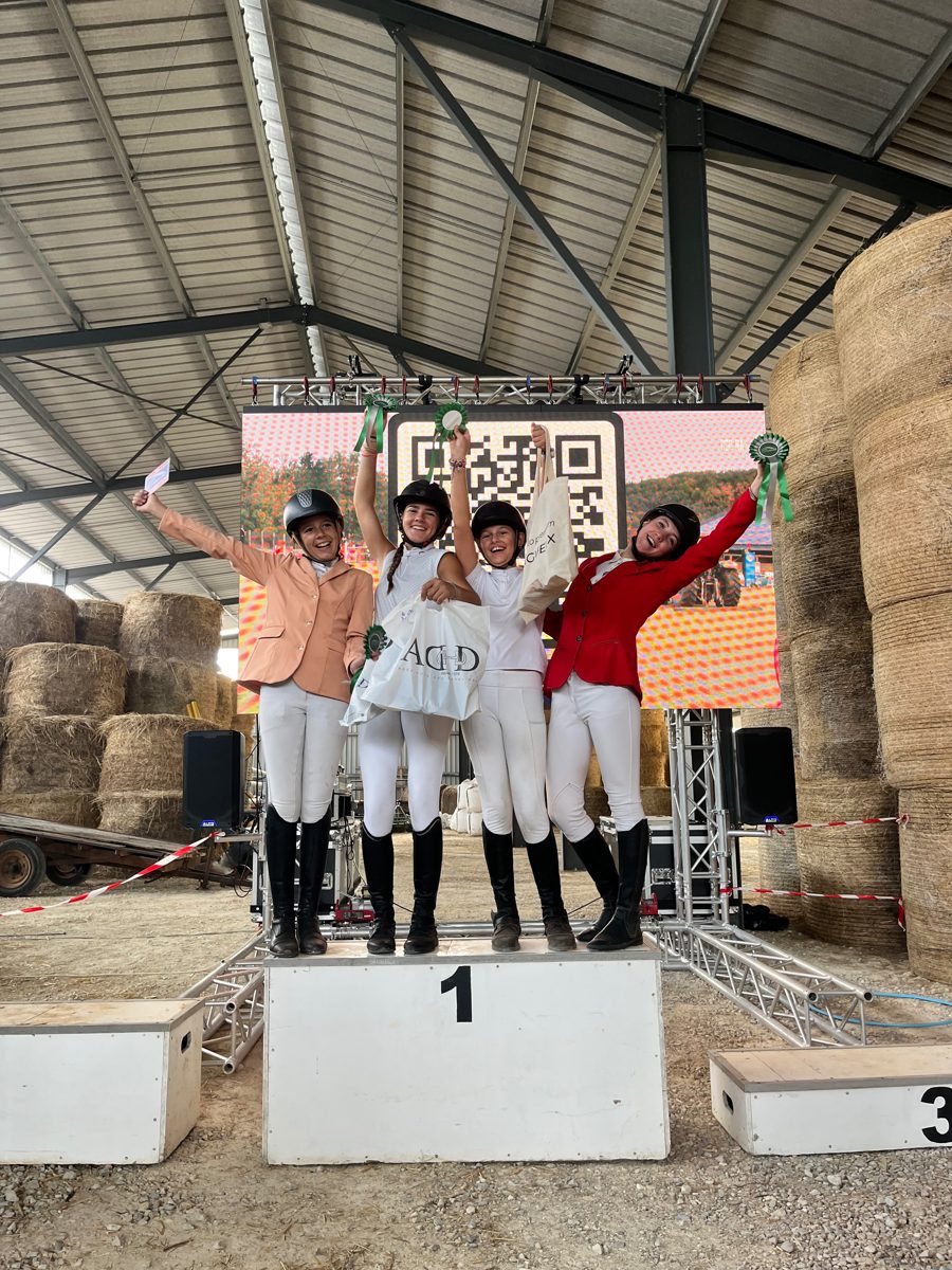 Quatre cavalières sur le podium, rosettes en main, après une compétition