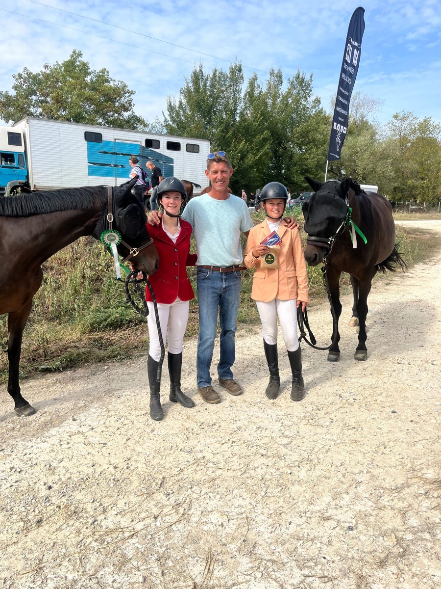 Deux jeunes cavalières avec leurs chevaux et leurs rosettes après une compétition